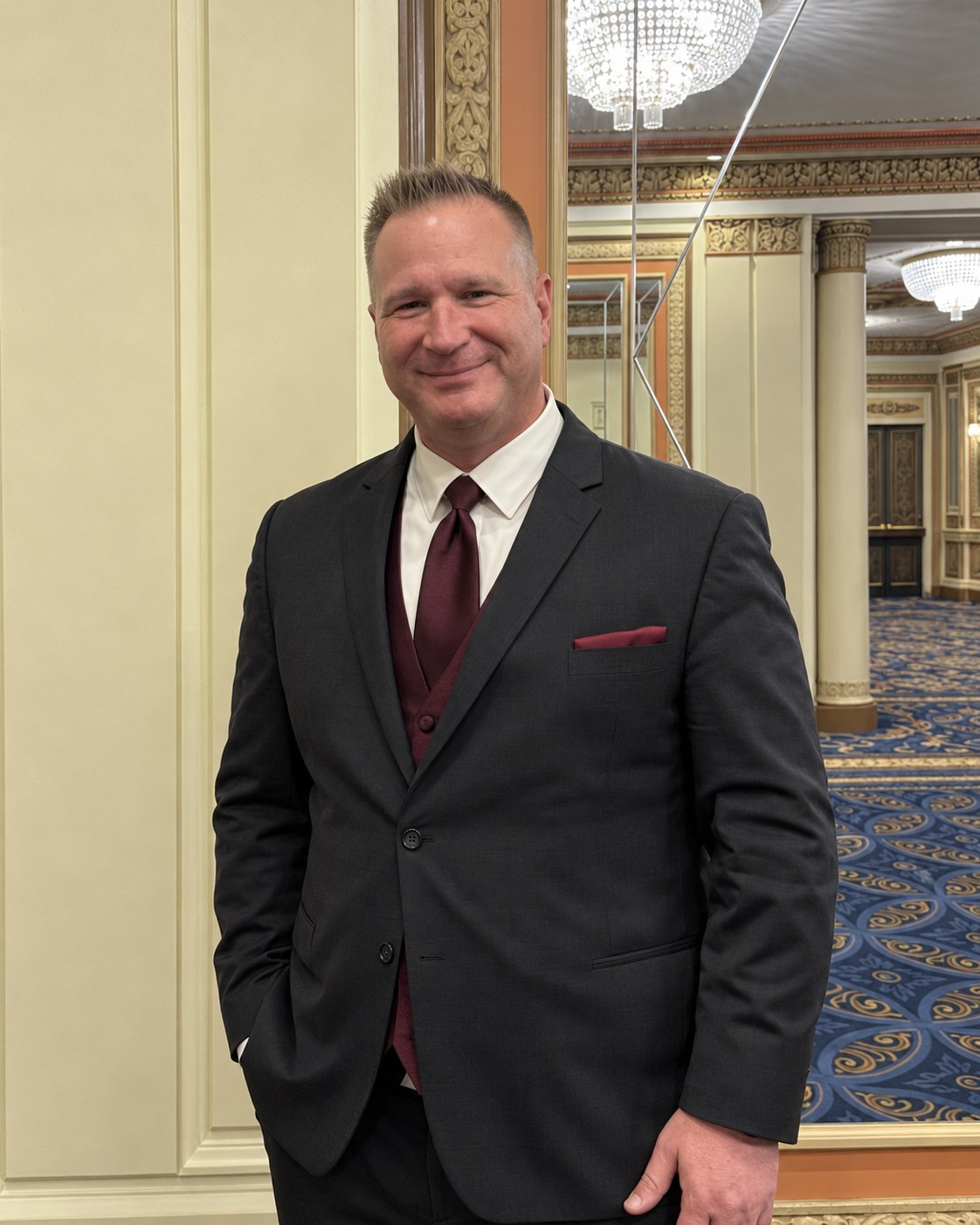 Jason Frovich wearing a dark suit with a burgundy tie